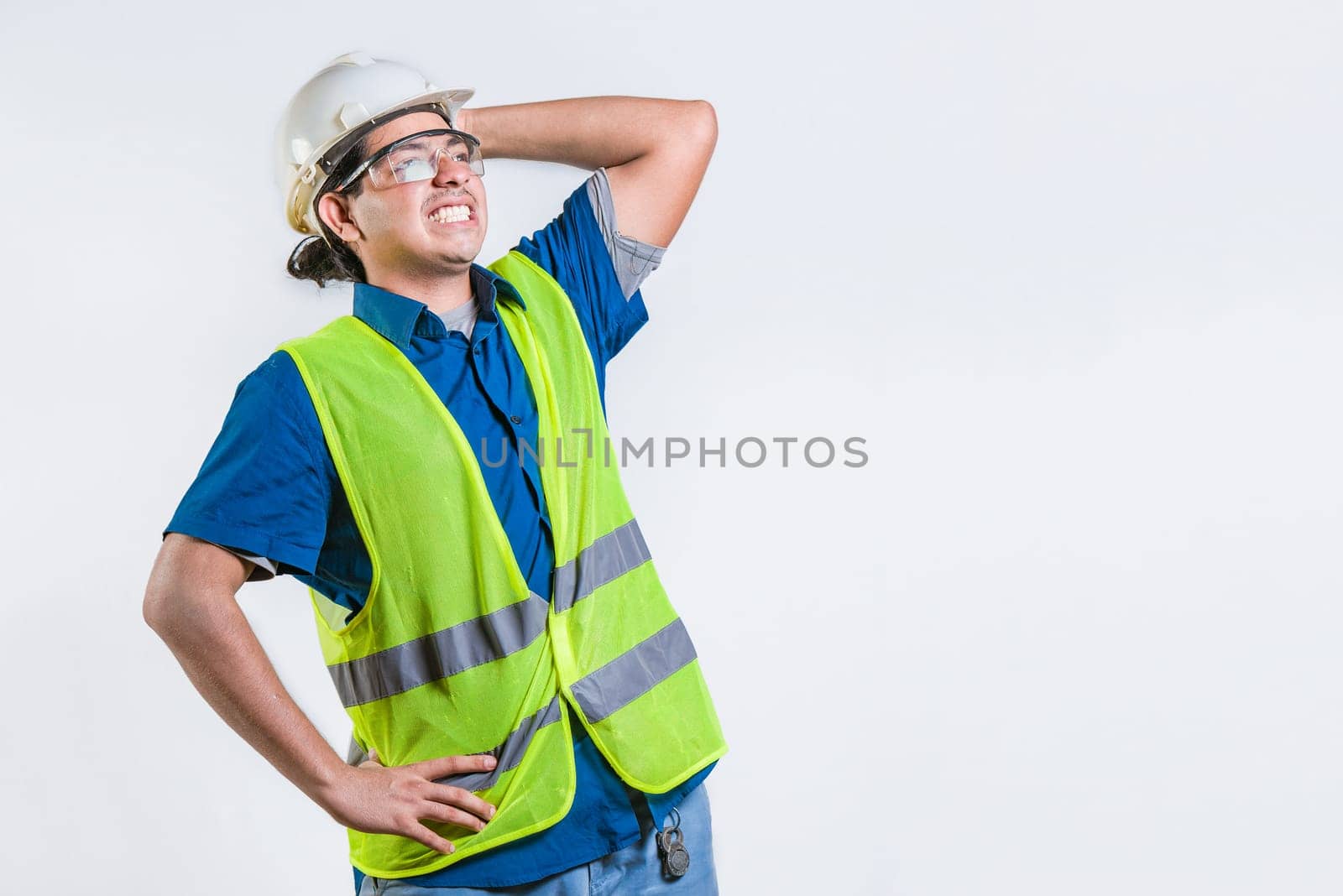 Engineer in problems holding head isolated. Troubled young engineer holding head isolated. Worried builder engineer holding head