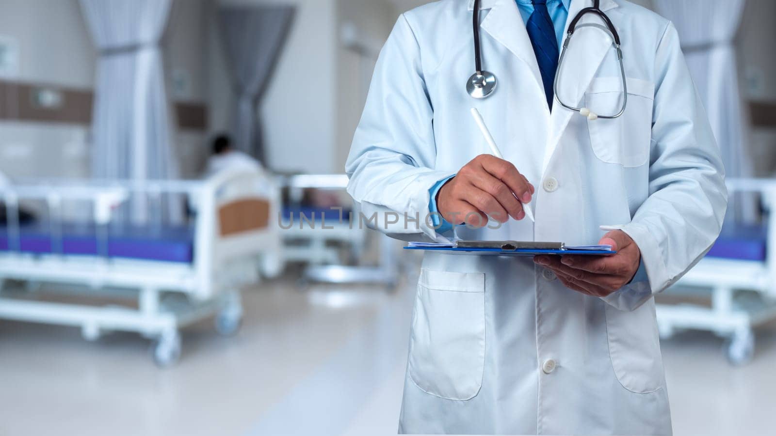 Doctor with stethoscope in white coat holding clipboard standing on the background inside a hospital, Writing medical record diagnosis, Close up, Healthcare and medicine, Concept of treating disease.