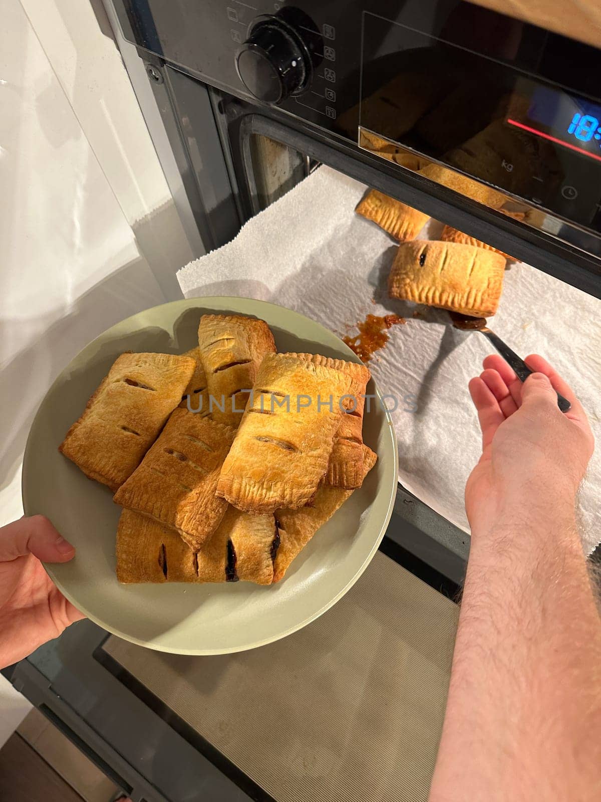 Freshly baked pastries are being taken out of the oven, steaming and golden brown, ready to be served on a green plate. Aroma of crispy dough fills the cozy kitchen, evoking a sense of warmth and homemade goodness.