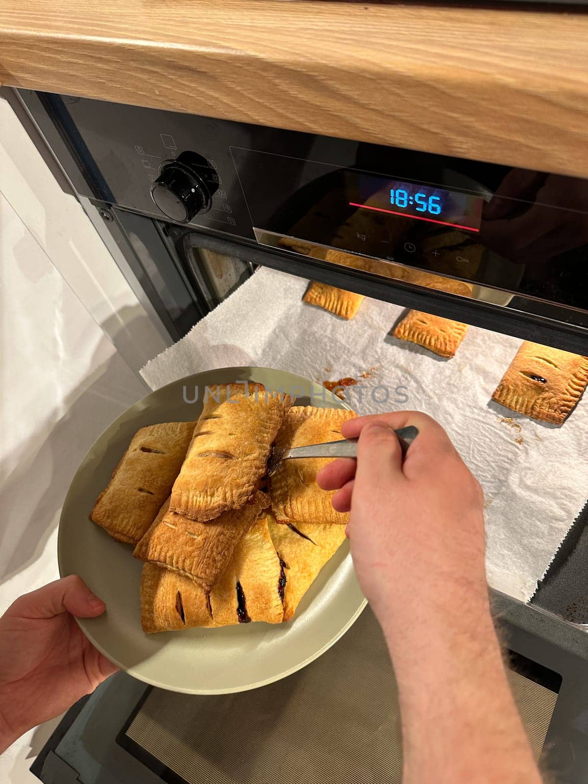 Freshly baked pastries are being taken out of the oven, steaming and golden brown, ready to be served on a green plate. Aroma of crispy dough fills the cozy kitchen, evoking a sense of warmth and homemade goodness.