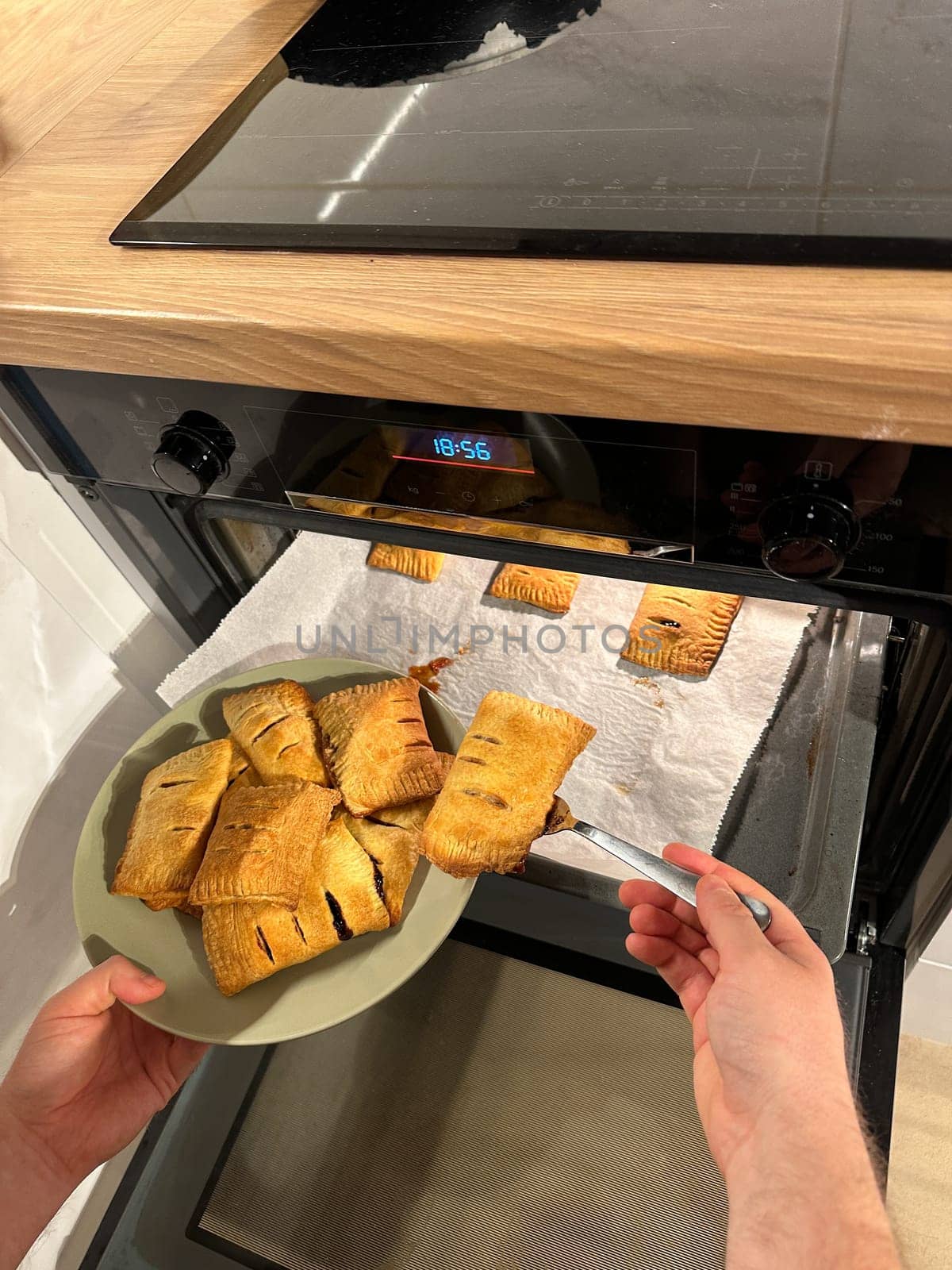 Freshly baked pastries are being taken out of the oven, steaming and golden brown, ready to be served on a green plate. Aroma of crispy dough fills the cozy kitchen, evoking a sense of warmth and homemade goodness.