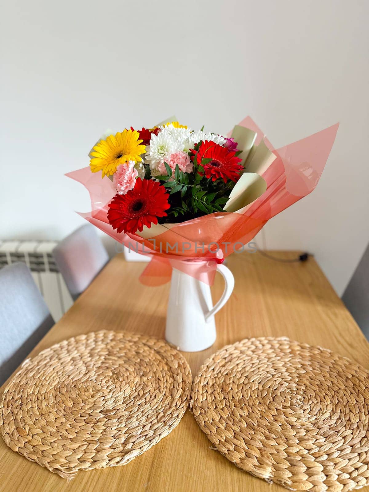 Vibrant bouquet of colorful flowers arranged in a white vase brightens up the room. the mixture of red, yellow, and pink blooms creates a cheerful and lively atmosphere, perfect for any celebration