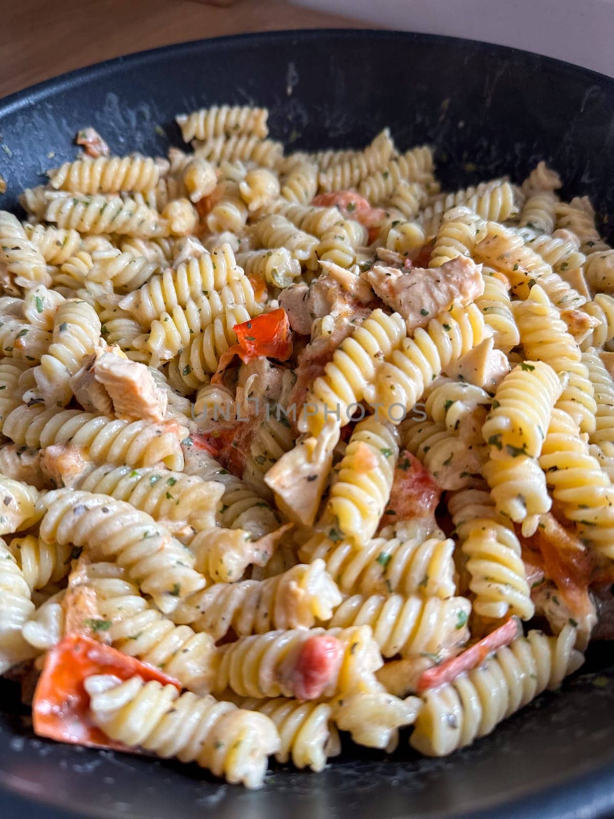 Delicious bowl of creamy rotini pasta mixed with pieces of chicken and vibrant vegetables is served fresh and ready to eat. Dish showcases a perfect blend of flavors and textures, making it an appetizing choice for any meal.