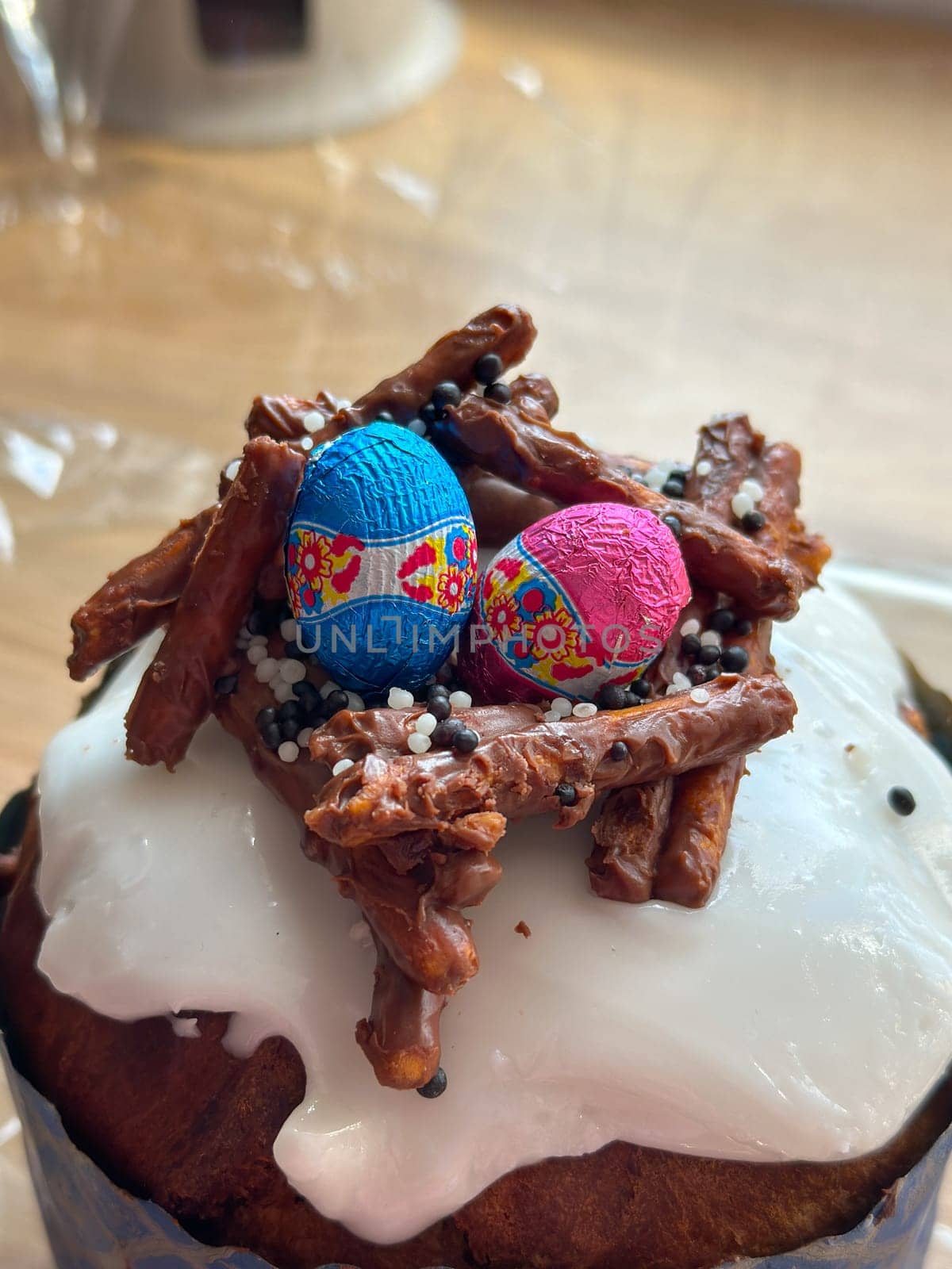 Festive easter cake is decorated with colorful chocolate eggs and crunchy pretzel sticks, creating a nest on top. Christian spring celebrations.