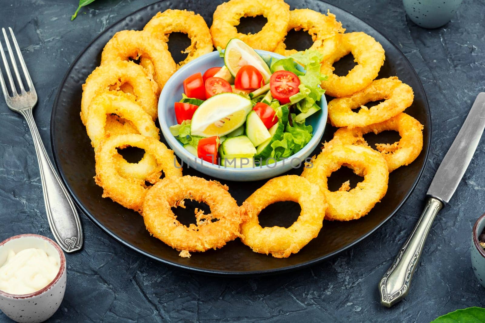 Fried squids or octopus (calamari) with fresh vegetable salad.