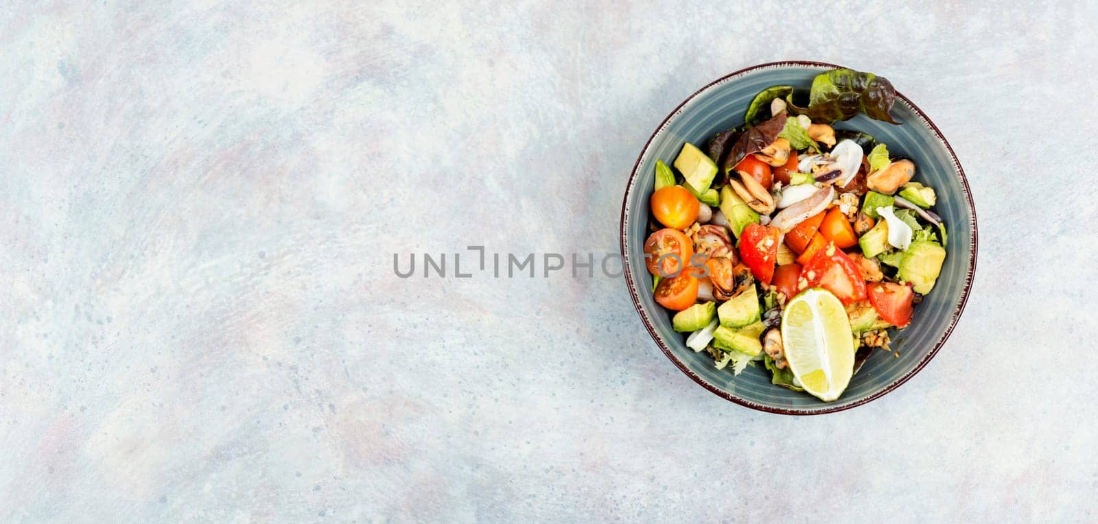 Seafood salad with shrimp, octopus, mussels, tomatoes, avocado and mixed greens. Healthy food. Flat lay with copy space