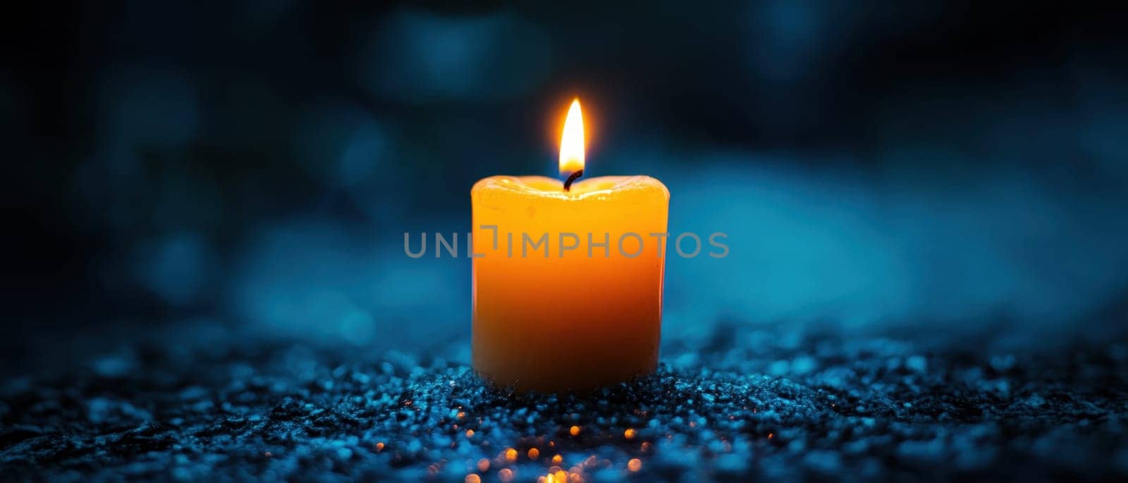 A yellow candle burns gently in a darkened space casting a warm glow over a reflective surface creating a tranquil atmosphere.
