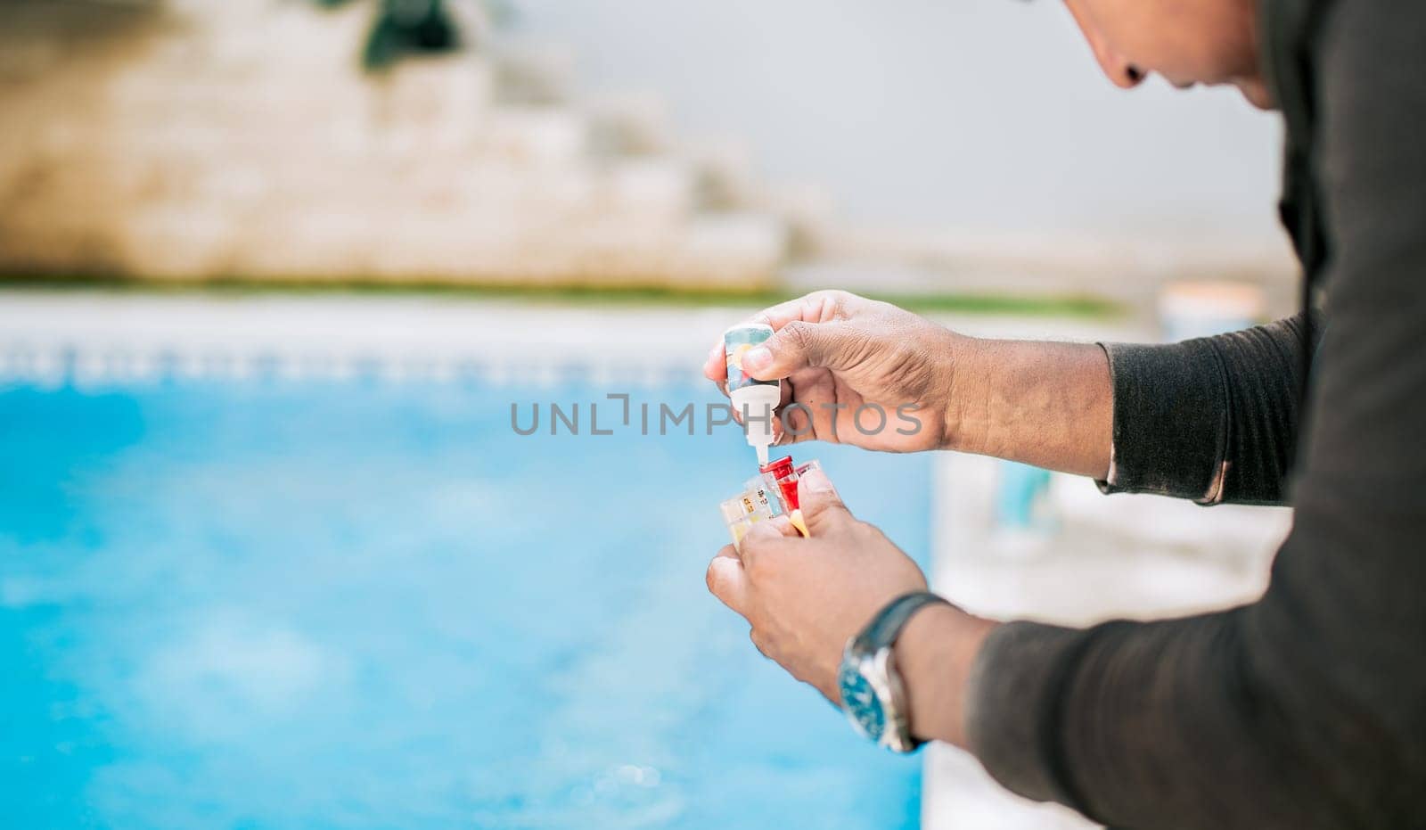 Man using tester kit to measure chlorine and ph in swimming pools. Person testing the PH of the swimming pool