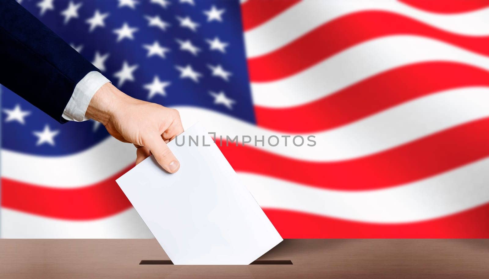 USA presidential elections. Hand holding ballot in voting ballot box with USA flag in background