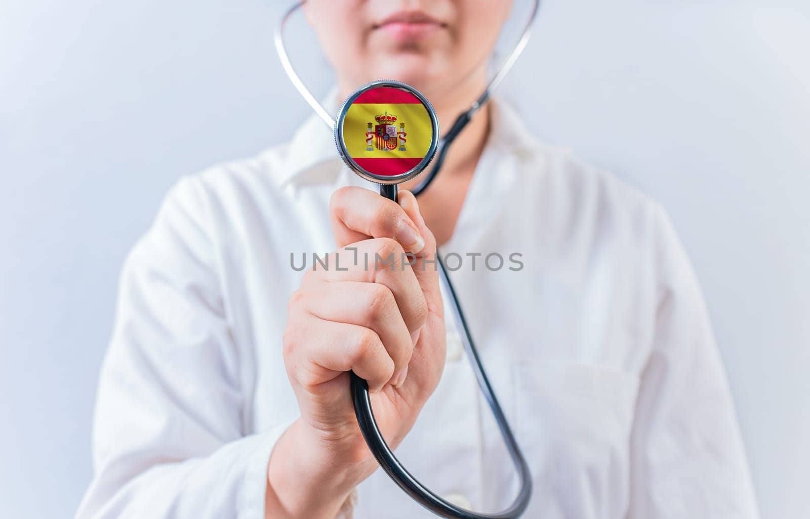 Female doctor holding stethoscope with Spain flag. Spanish Health and Care concept