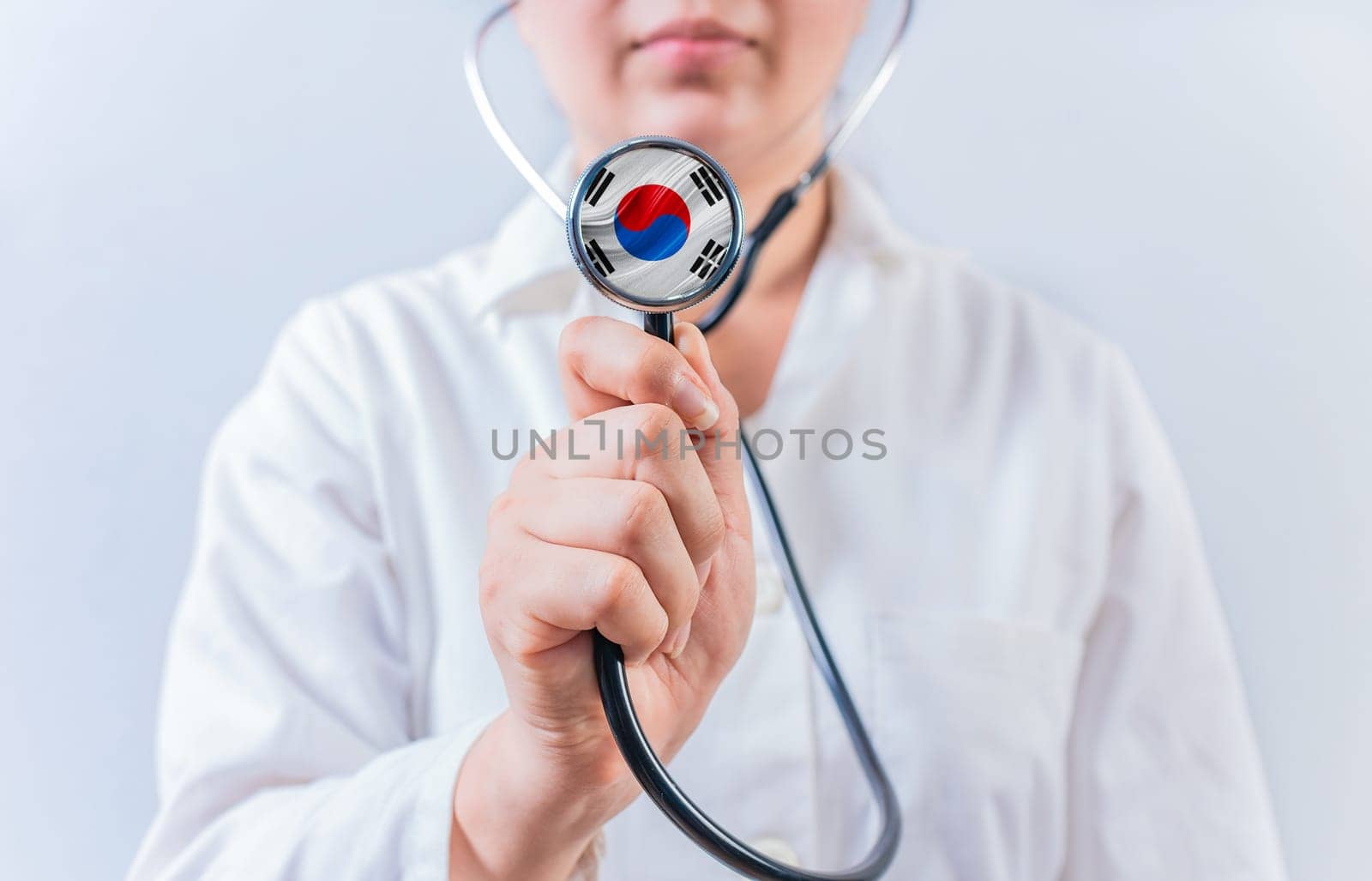 Female doctor holding stethoscope with South Korean flag. South Korean Health and Care concept