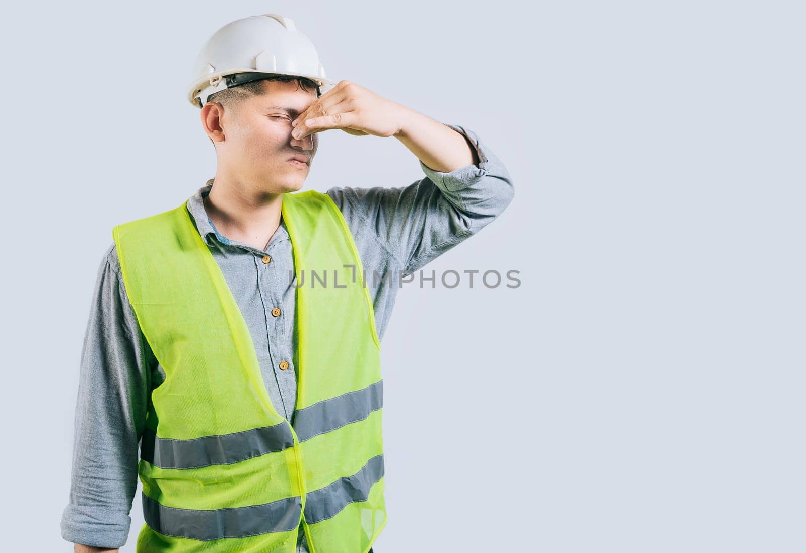 Man engineer covering her nose from a bad smell isolated isolated. Displeased young engineer holding her nose isolated