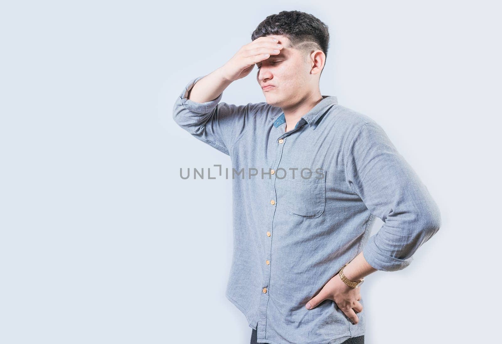 Tired man holding his head isolated. Worried young man holding his forehead isolated