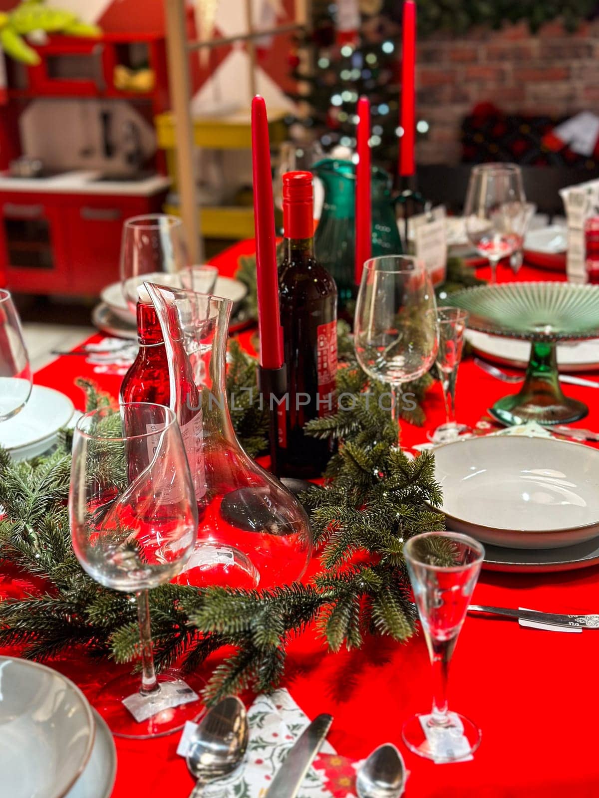 Christmas set table is adorned with festive decorations, ready for a joyful winter holiday gathering. Vibrant red tablecloth and elegant tableware create a warm and inviting atmosphere.