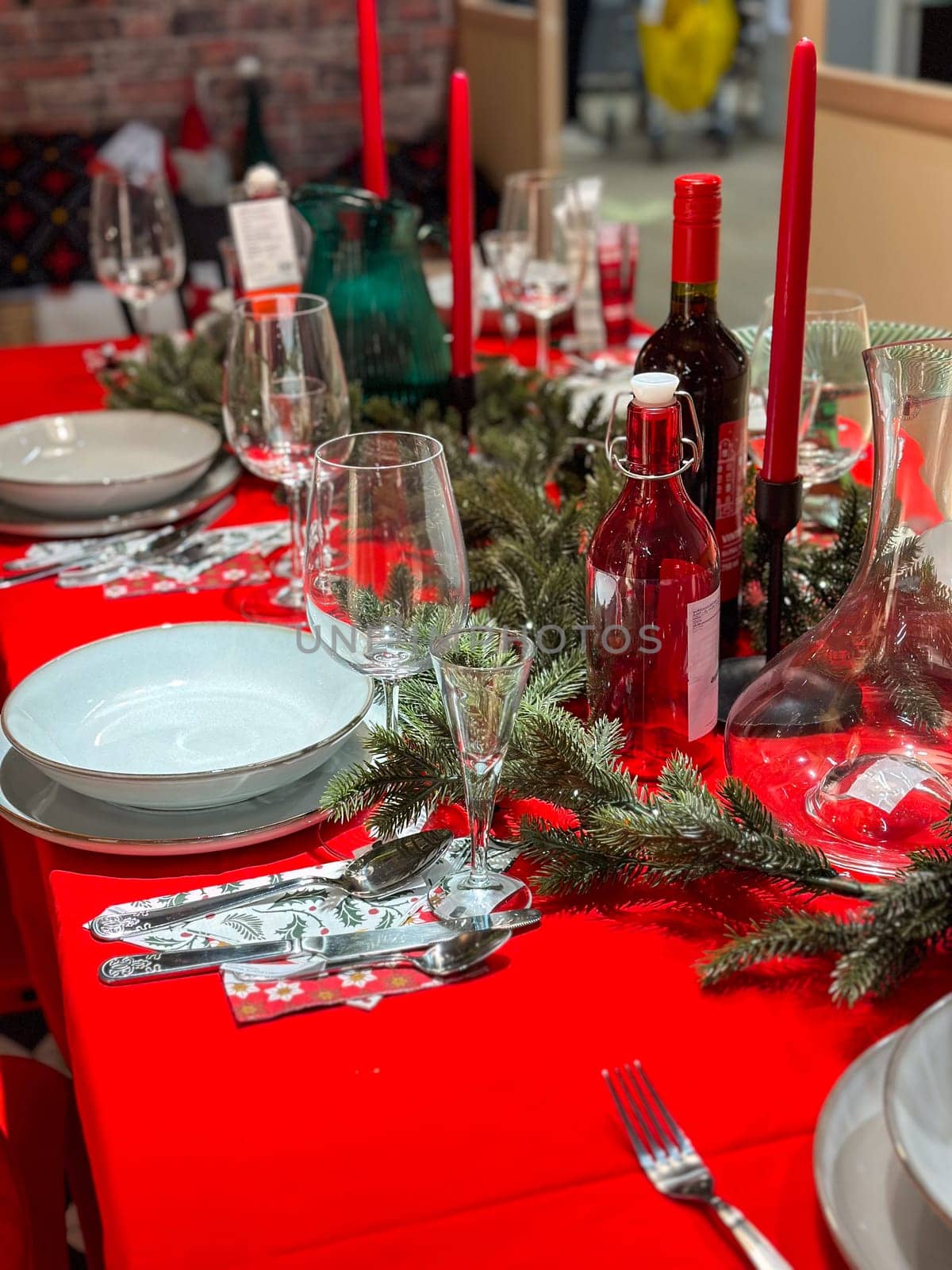 Christmas set table is adorned with festive decorations, ready for a joyful winter holiday gathering. Vibrant red tablecloth and elegant tableware create a warm and inviting atmosphere.