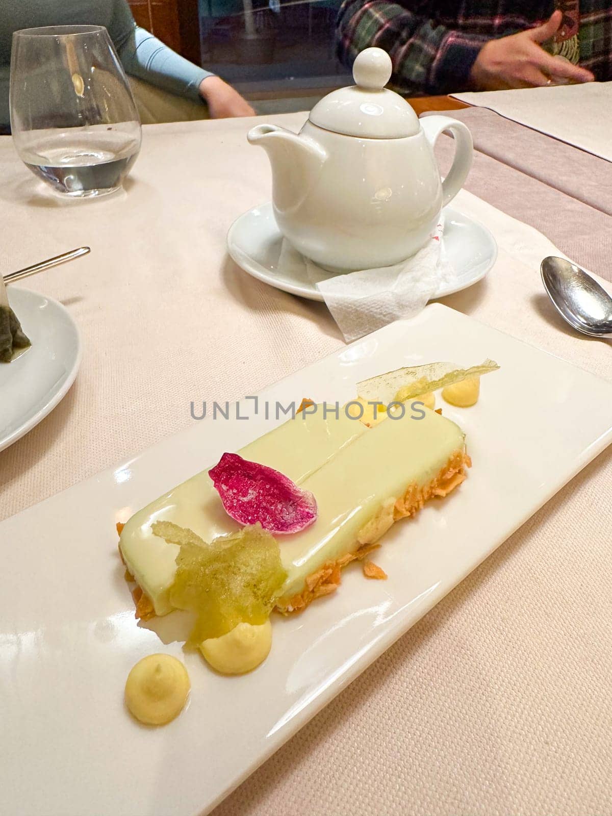 Delicate dessert elegantly plated features a creamy bar adorned with colorful edible petals and crispy accents, artistry of fine pastry making. this exquisite image highlights the luxurious world of gourmet sweets and fine dining experiences