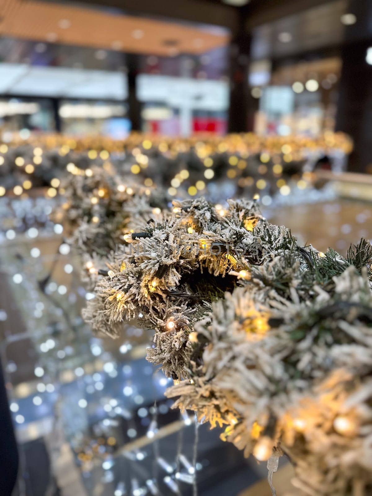 Close-up shot captures a beautifully frosted garland adorned with twinkling lights in Christmas festive indoor setting. Warm glow creates a magical atmosphere, perfect for the holiday season.