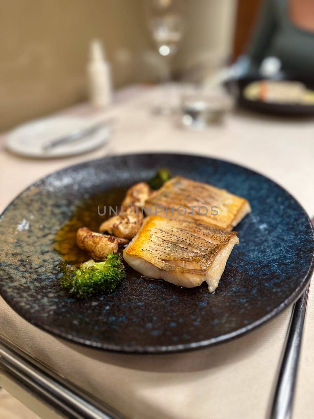 Plated gourmet dish features succulent fish fillets accompanied by roasted cauliflower and broccoli, set against a rich, dark sauce. this image captures an exquisite dining experience, showcasing the artistry of haute cuisine.