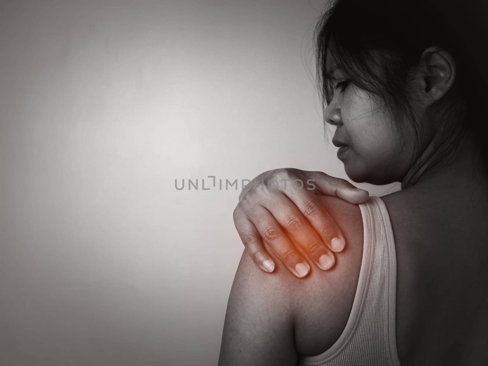 Woman with acute pain shoulder with neck pain on gray background, Shoulder inflammation and arm, Female massaging her shoulder muscle spasm, Healthcare and medical concept, Injuries and medical.
