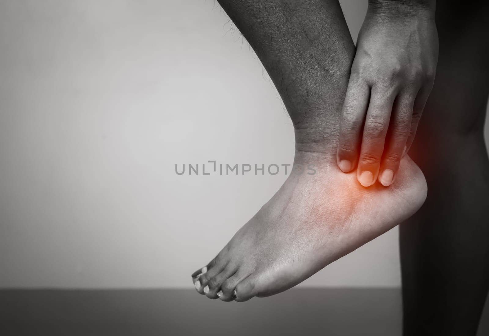Woman with acute pain ankle with leg pain on gray background, Ankle and leg treatment, Female massaging her ankle muscle spasm, Healthcare and medical concept, Injuries and medical concept.