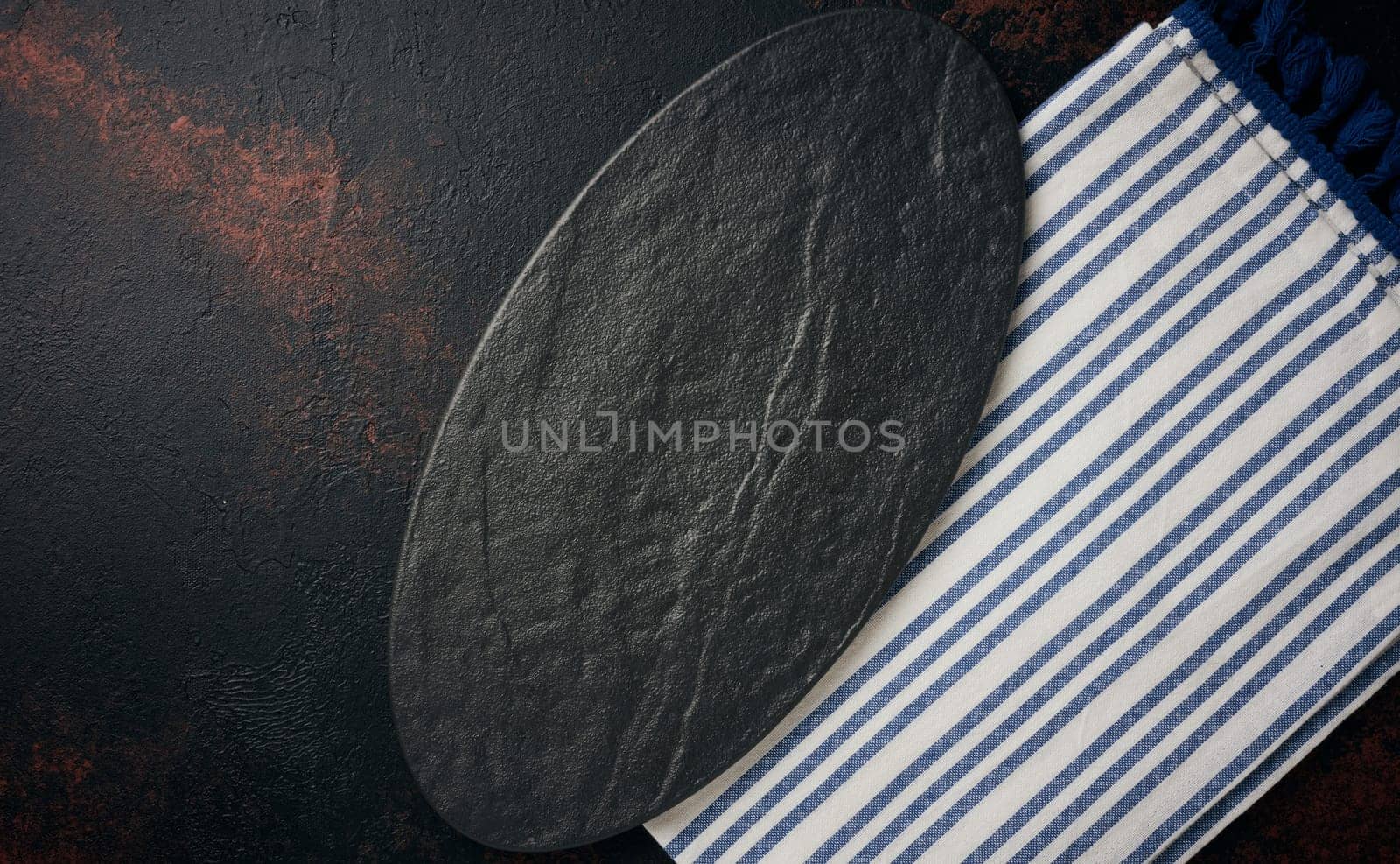 Oval stone kitchen board on black background, top view. Copy space