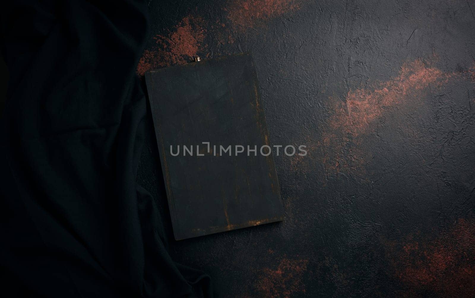 Empty black wooden cutting board and linen kitchen towel, top view. Copy space