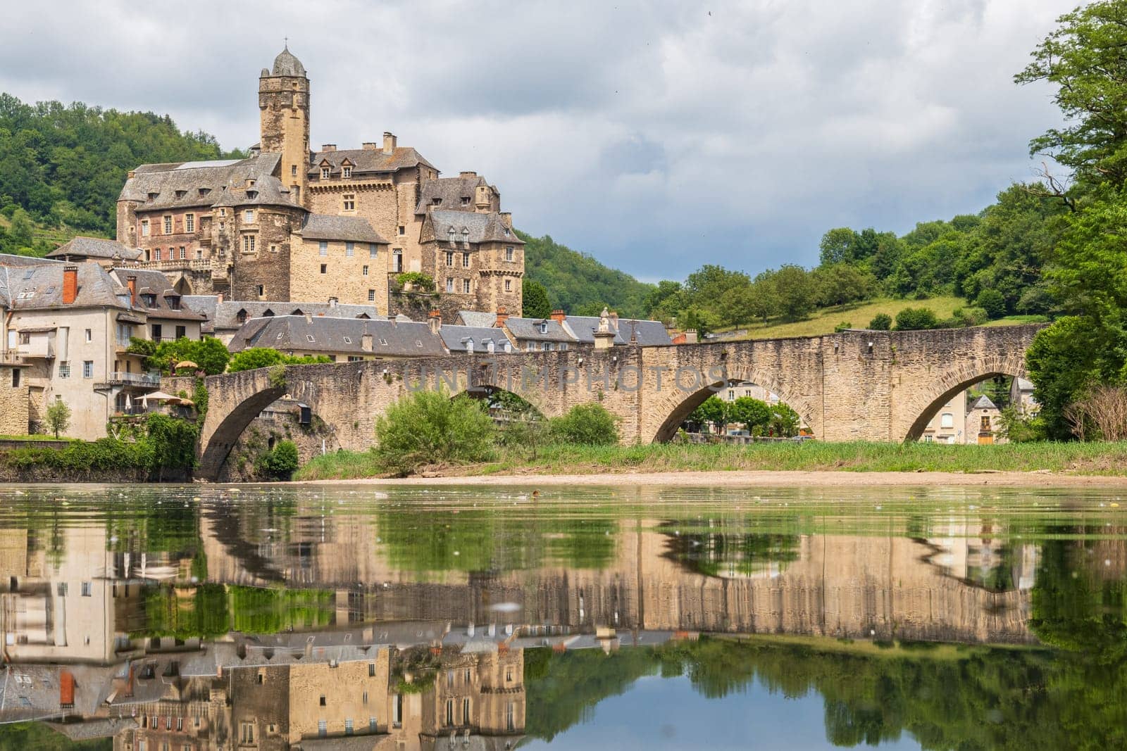 Estaing village, castle and medieval bridge reflecting over Lot river photographed in Aveyron, one of the most beautiful villages of France
