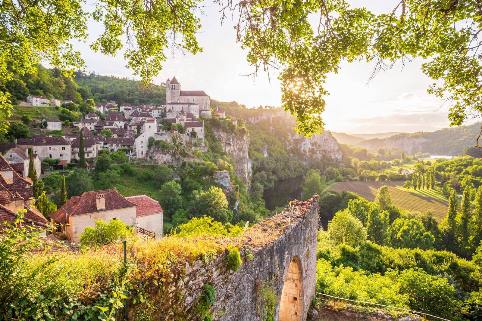Old cliffside village of Saint-Cirq-Lapopie, one of the most beautiful villages of France,  pleasantly framed by nature at the sunset in the Lot department, Occitanie region of South West France