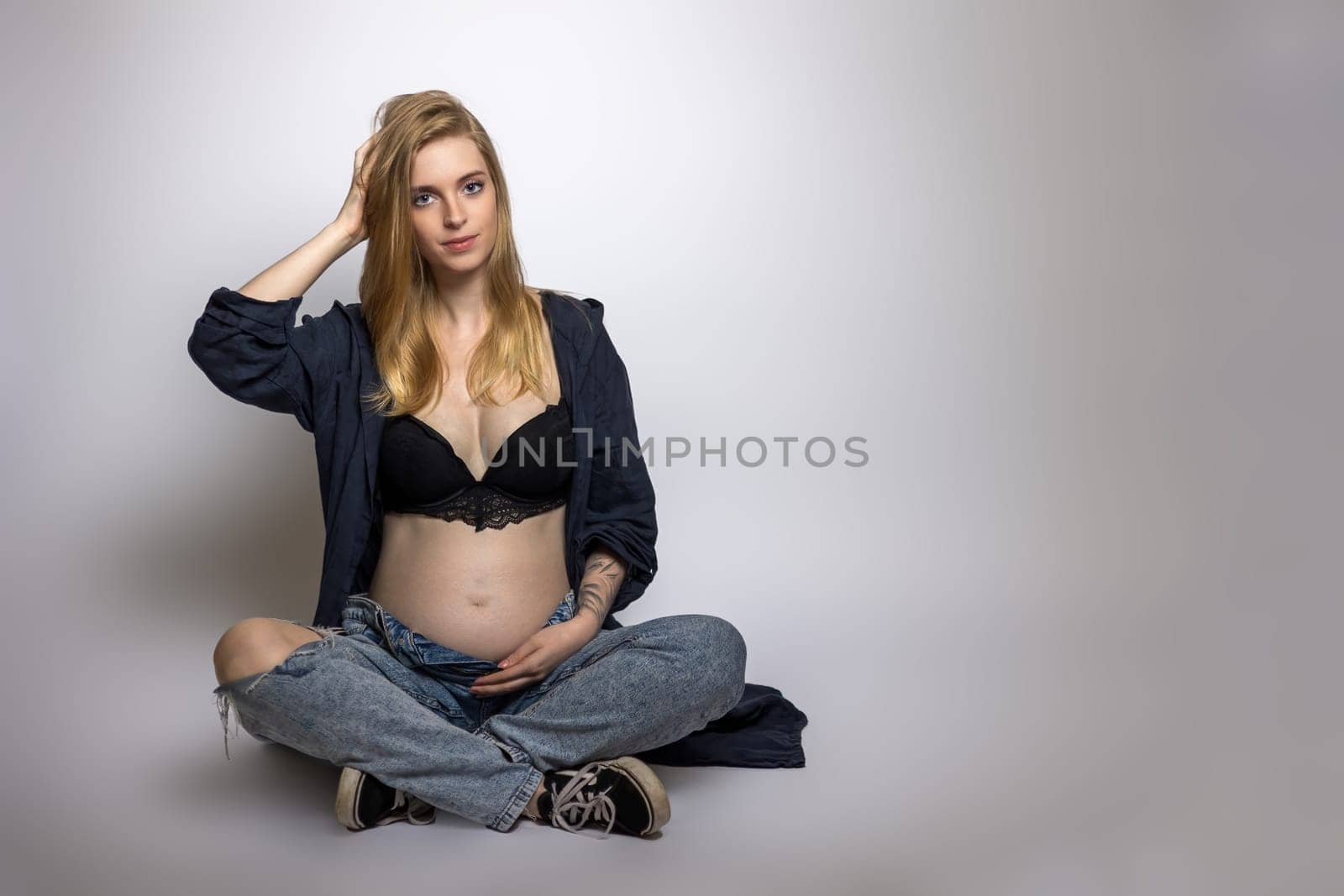 Studio shot of pregnant young woman posing on gray background.  Horizontally.