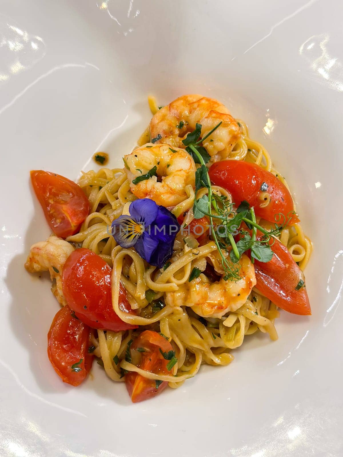 Shrimp pasta served with vibrant tomatoes and a touch of herbs. Delightful dish is beautifully garnished fresh flowers, flavor and elegance Italian cuisine.