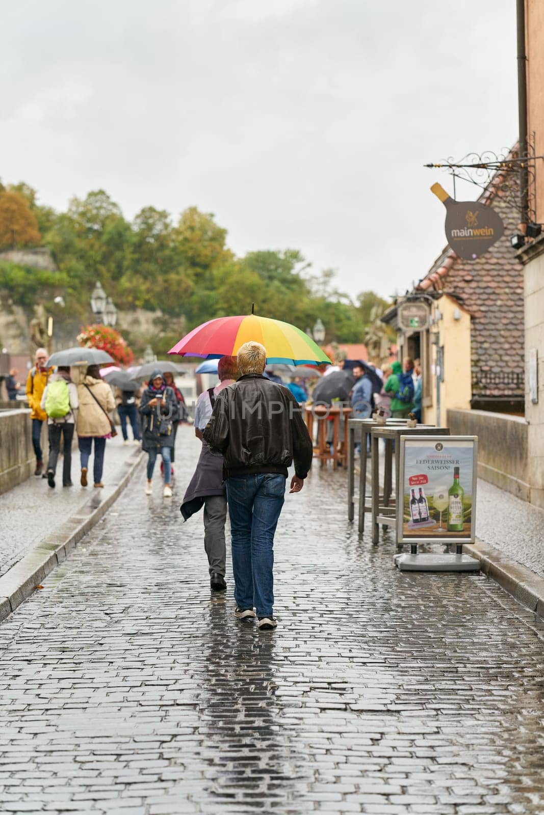 Tourists on the old Main Bridge, alte Mainbrücke in Wuerzburg in rainy weather with umbrellas