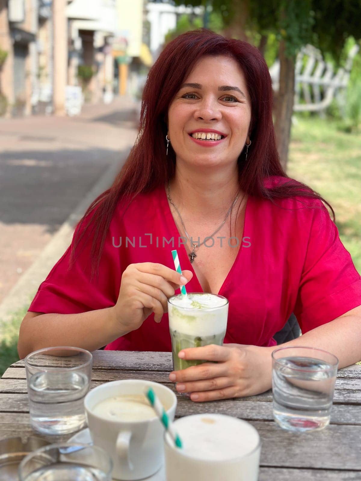 Woman enjoying a refreshing drink at an outdoor cafe in a vibrant setting. Relaxation and the joy of savoring a leisurely afternoon.