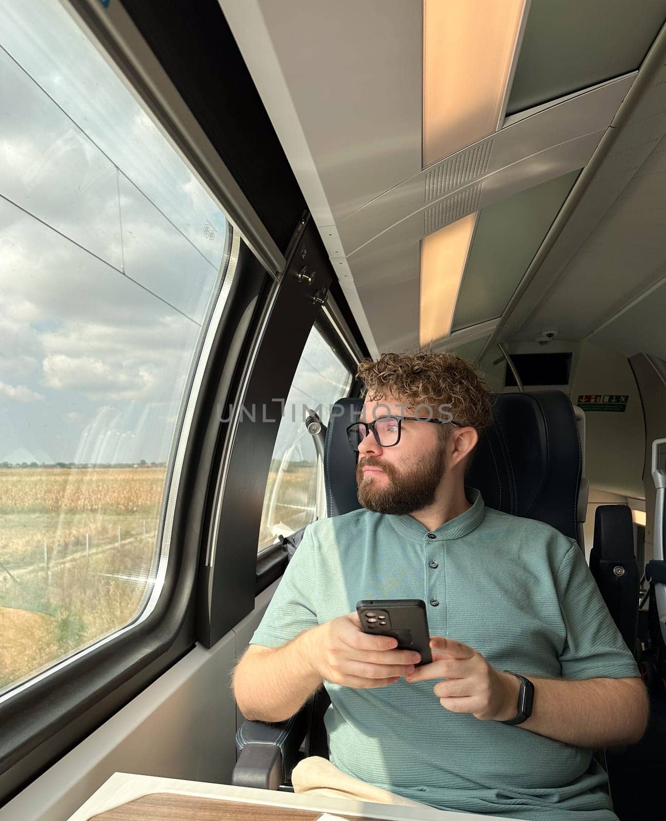 Man traveler enjoying a serene view from a train window. Calm and reflection during a peaceful journey.