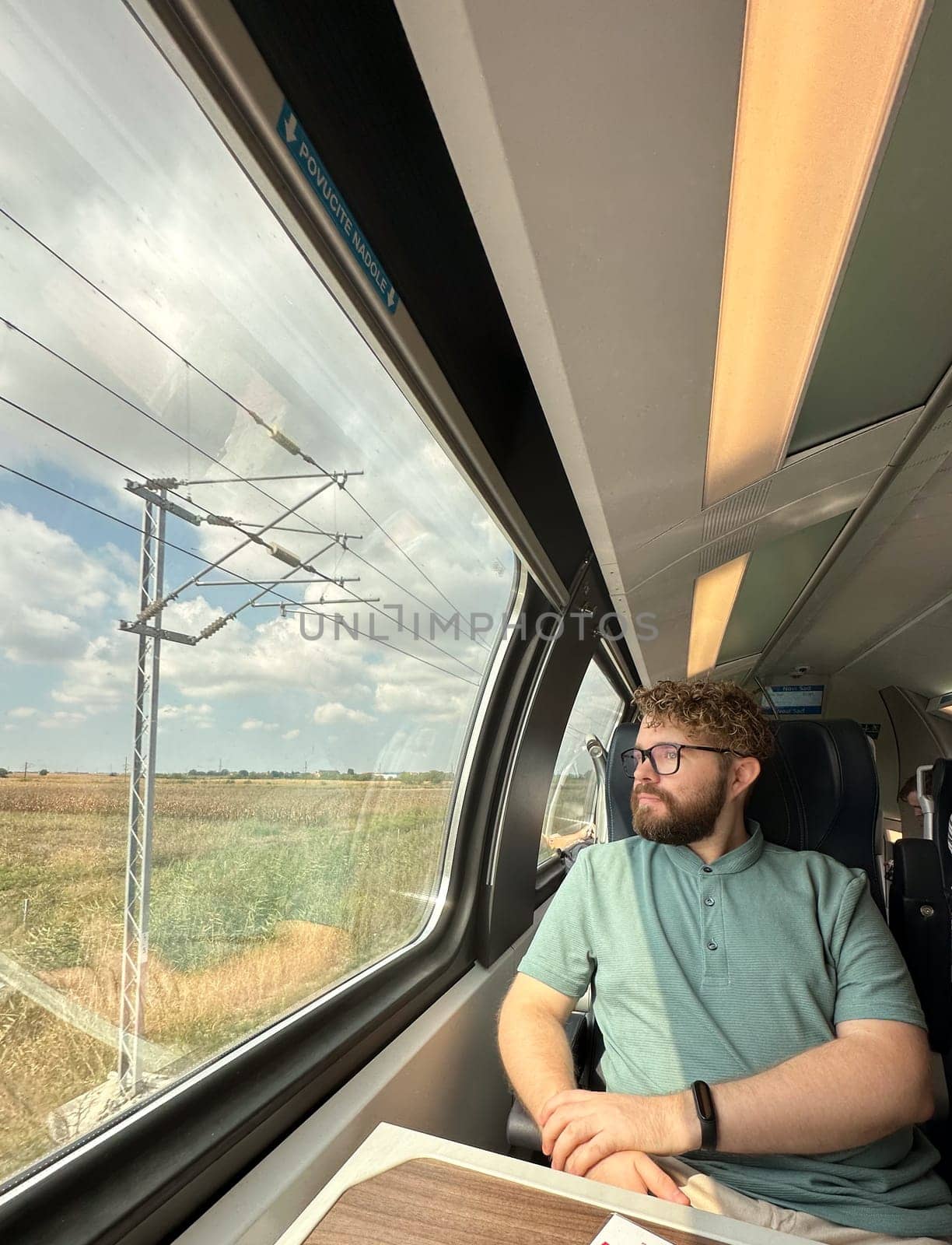 Man traveler enjoying a serene view from a train window. Calm and reflection during a peaceful journey.