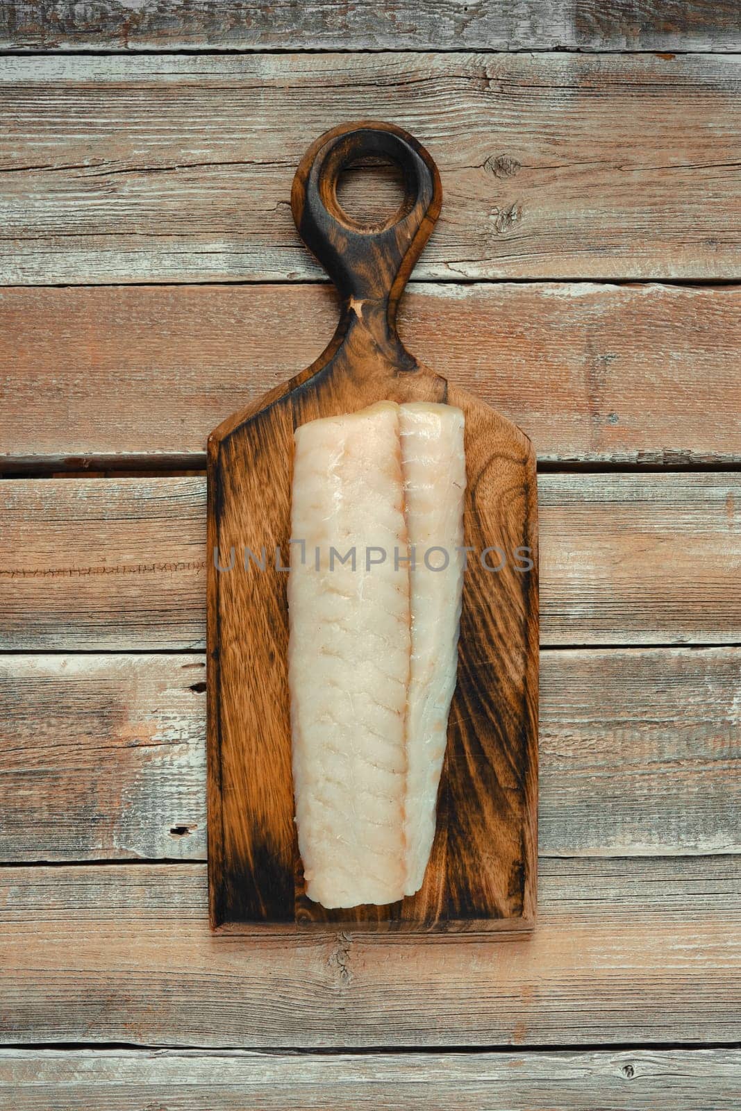 A clean, freshly sliced fillet of white fish rests on a handcrafted wooden cutting board