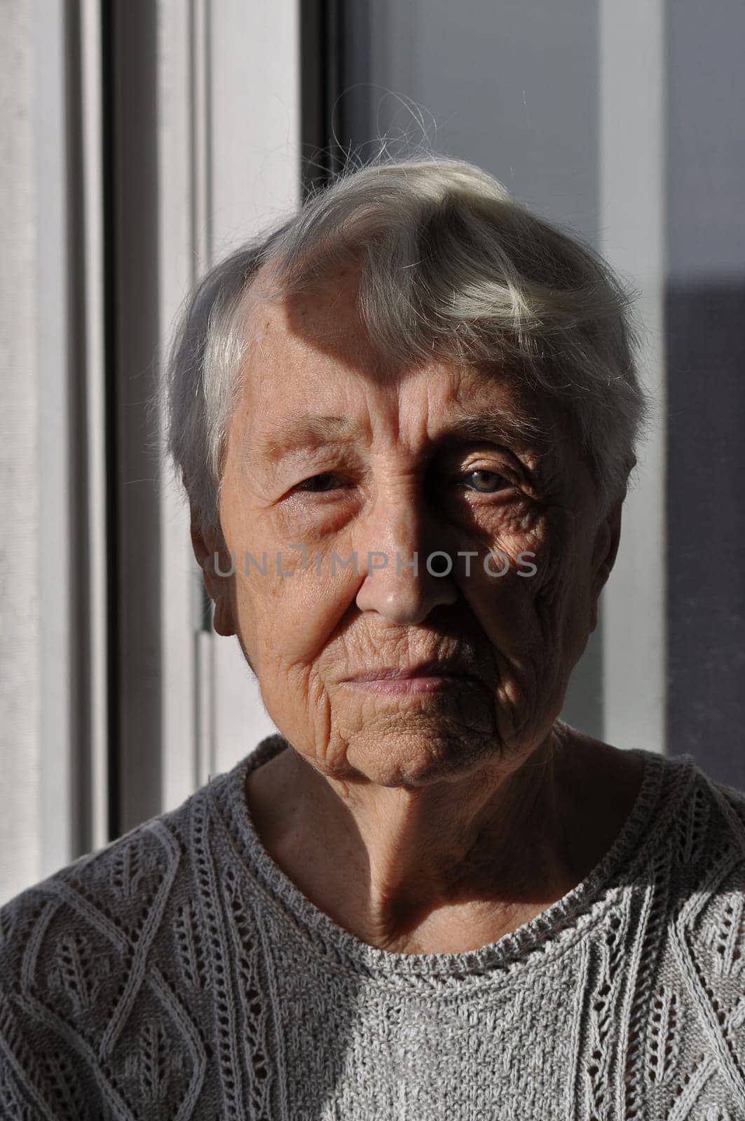 Head shot close up portrait of thoughtful senior woman worrying about personal health problems. Upset older female thinking of family troubles, feeling lonely, sitting at home.