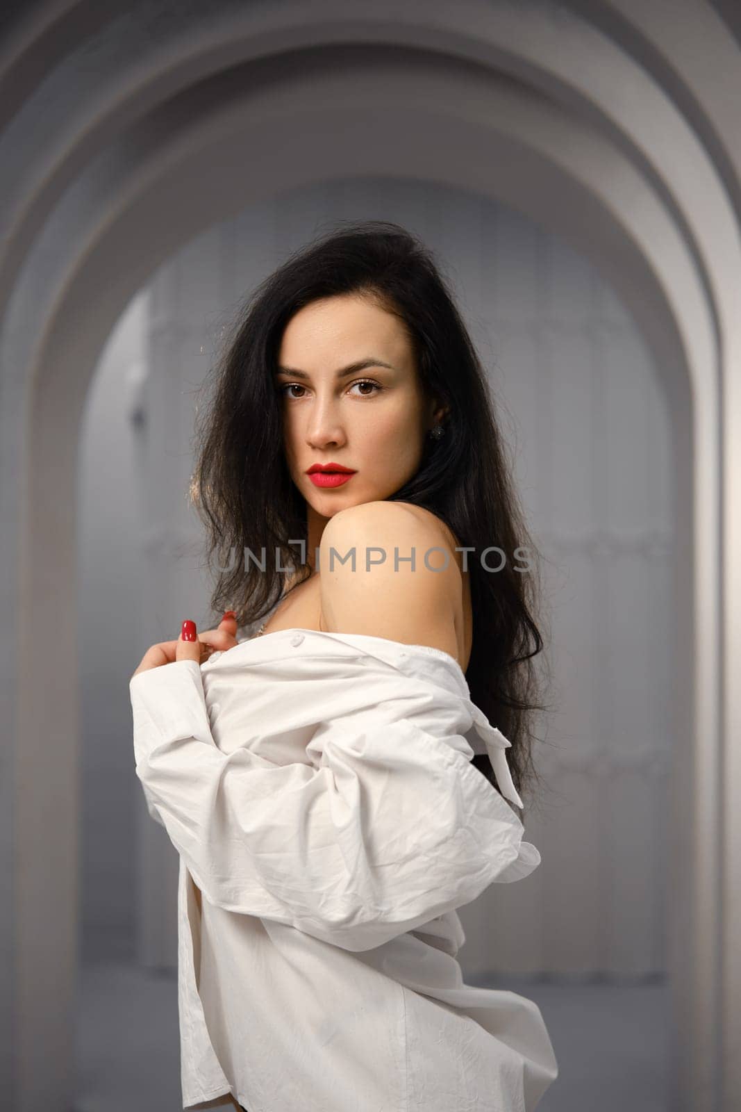 Brunette woman wearing a white off-the-shoulder shirt standing in profile in a corridor with a curved ceiling