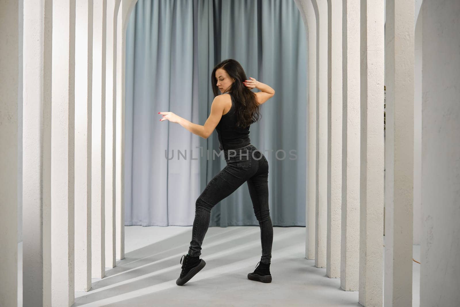 Young woman dancing in a hall with columns standing in profile
