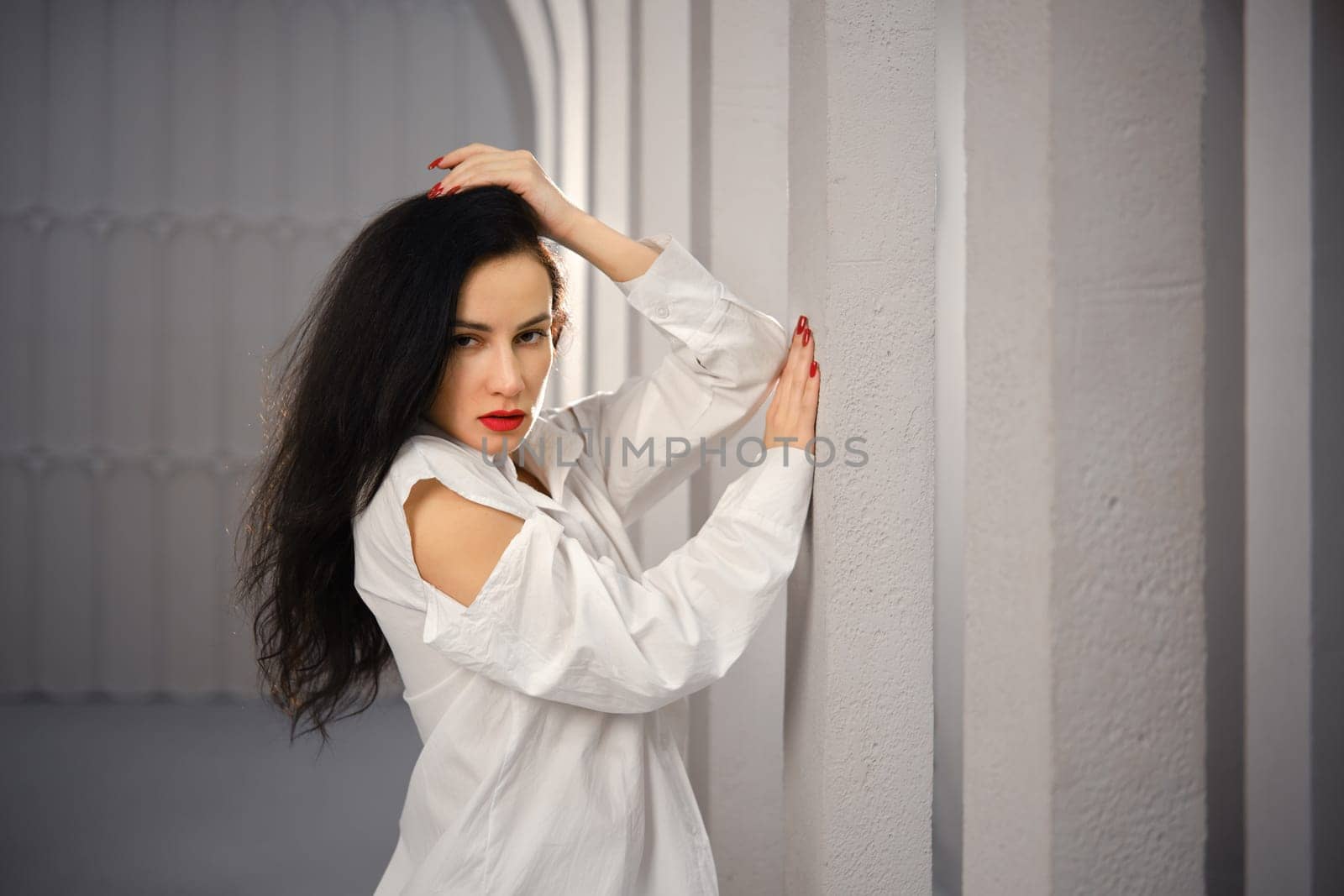 Strict woman rested her elbow against the column standing in profile