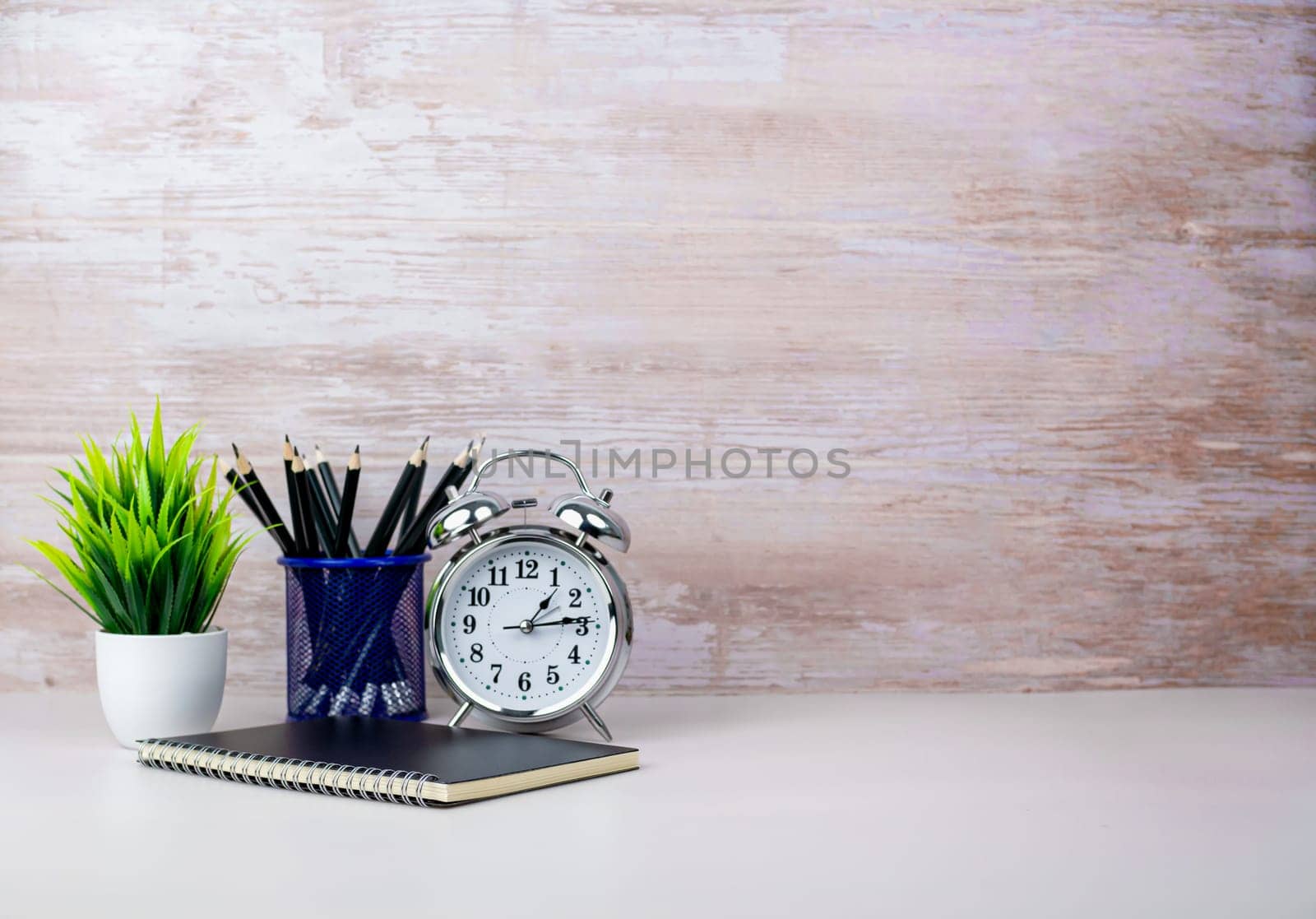 Workspace Mock up white table top with vintage notebook, pencils and green houseplant. Copy space desk with copy space for products display montage. Minimalist white workplace with supplies.