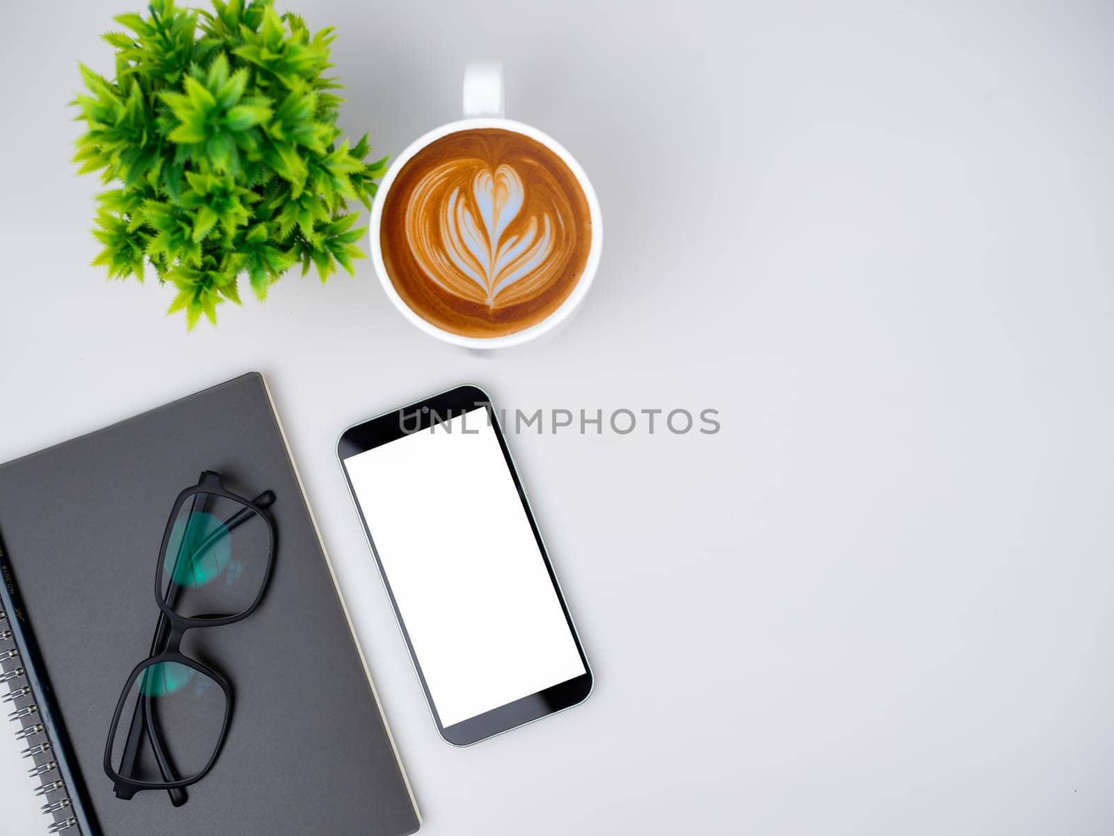 Top view of mock up modern workspace with blank screen smartphone, Coffee cup, Notebook, Pencil, Glasses. Office situation with keyboard and accessories isolated on white. Copy space, Flat lay.