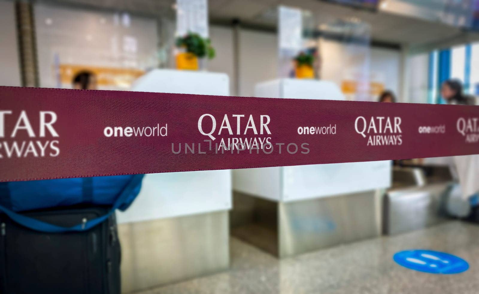 Doha, QA, May 22 2022  Close-up of Qatar Airways branded ribbon at an airport check-in counter. The visible logos include Qatar Airways and Oneworld alliance.