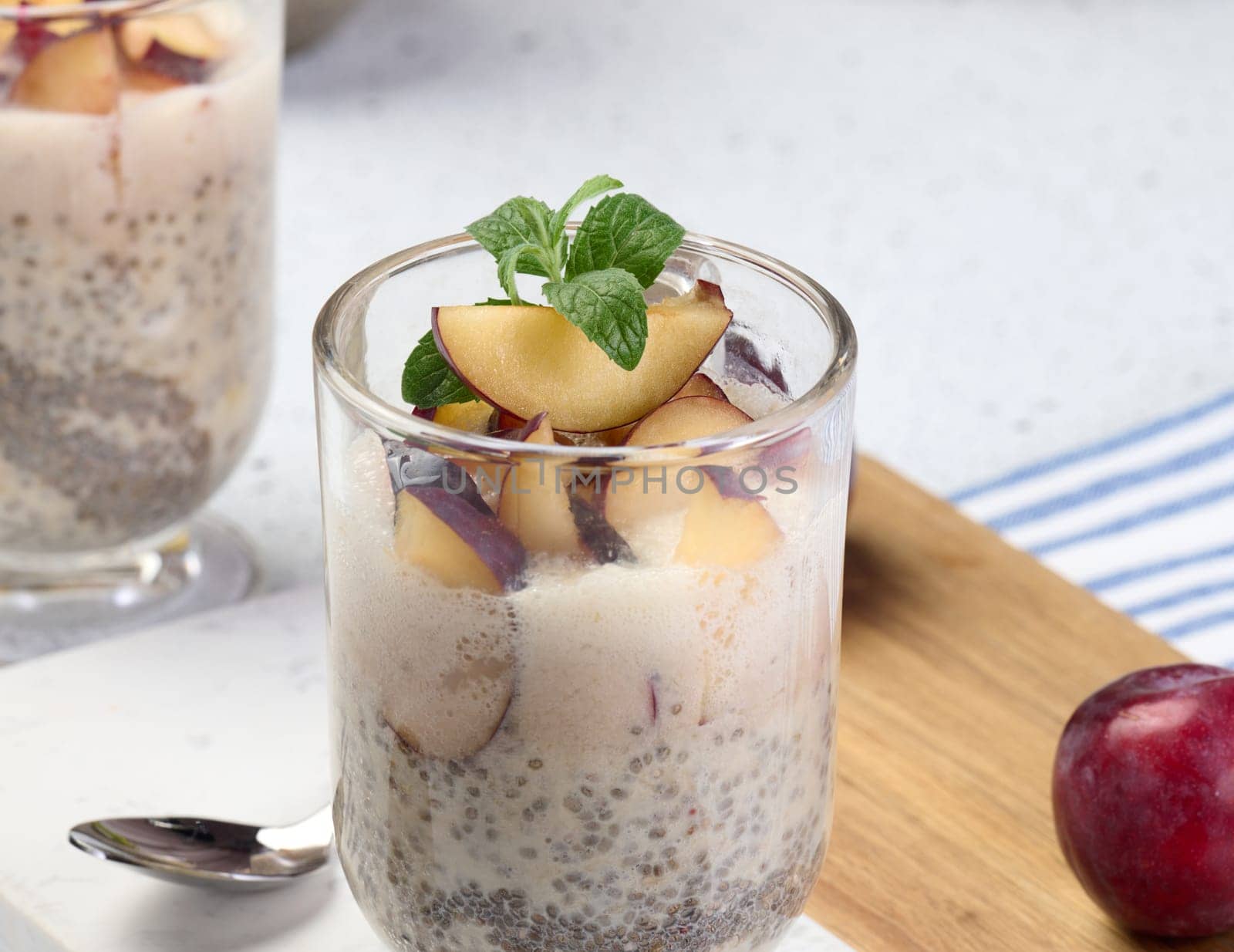 A glass of chia seeds and yogurt, with pieces of plum