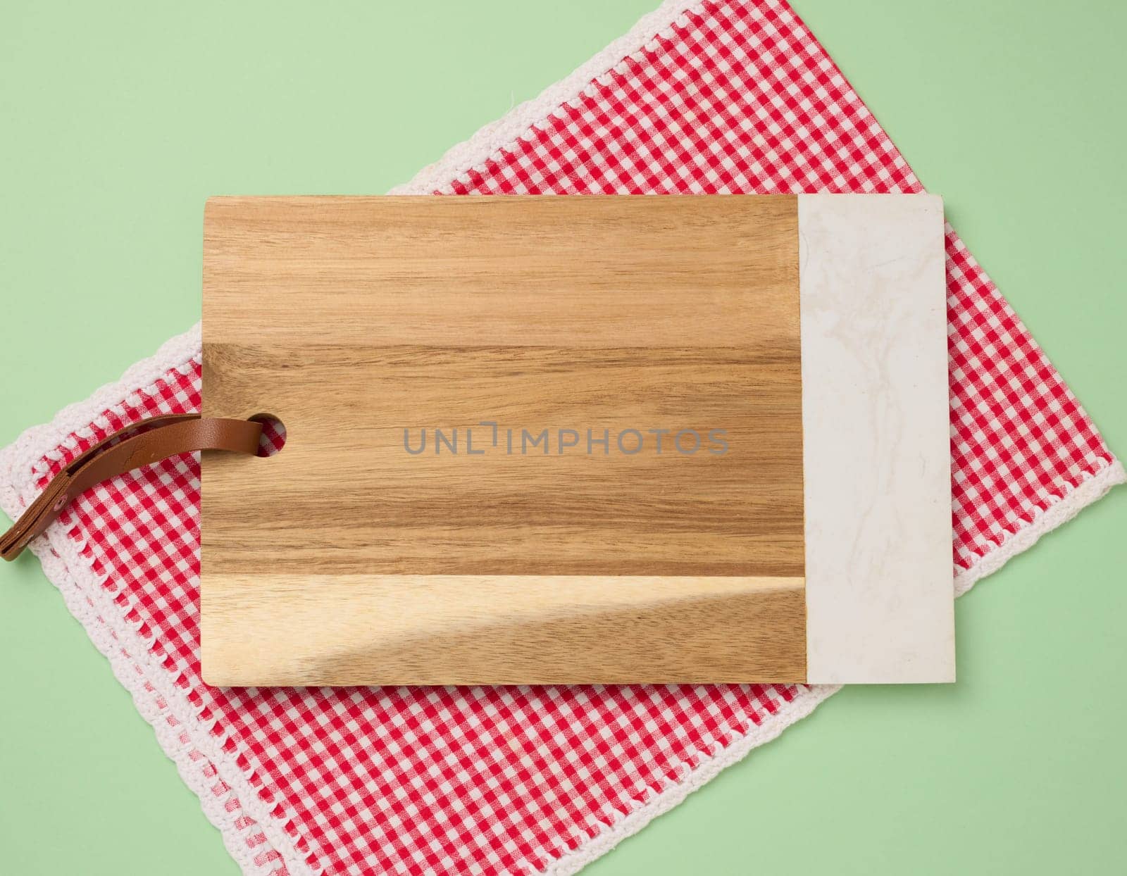 Empty rectangular wooden kitchen cutting board on green background, top view