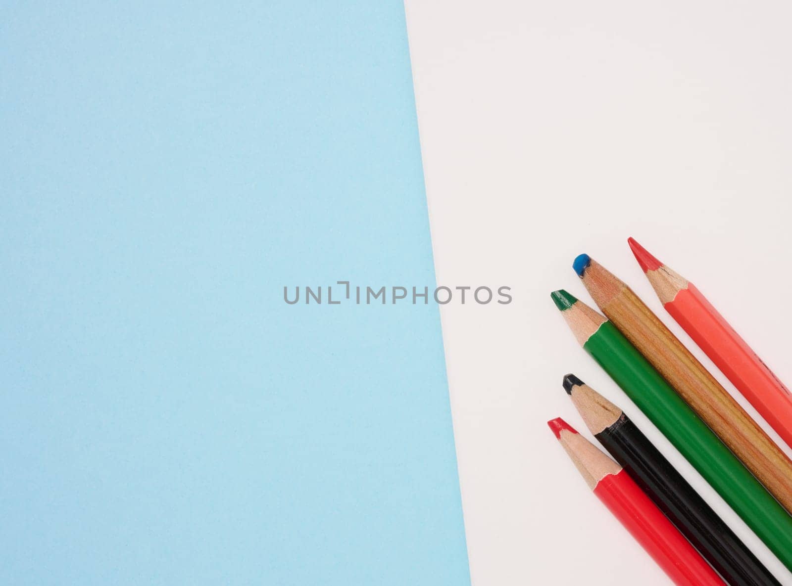 Multicolored wooden pencils on a blue background, top view