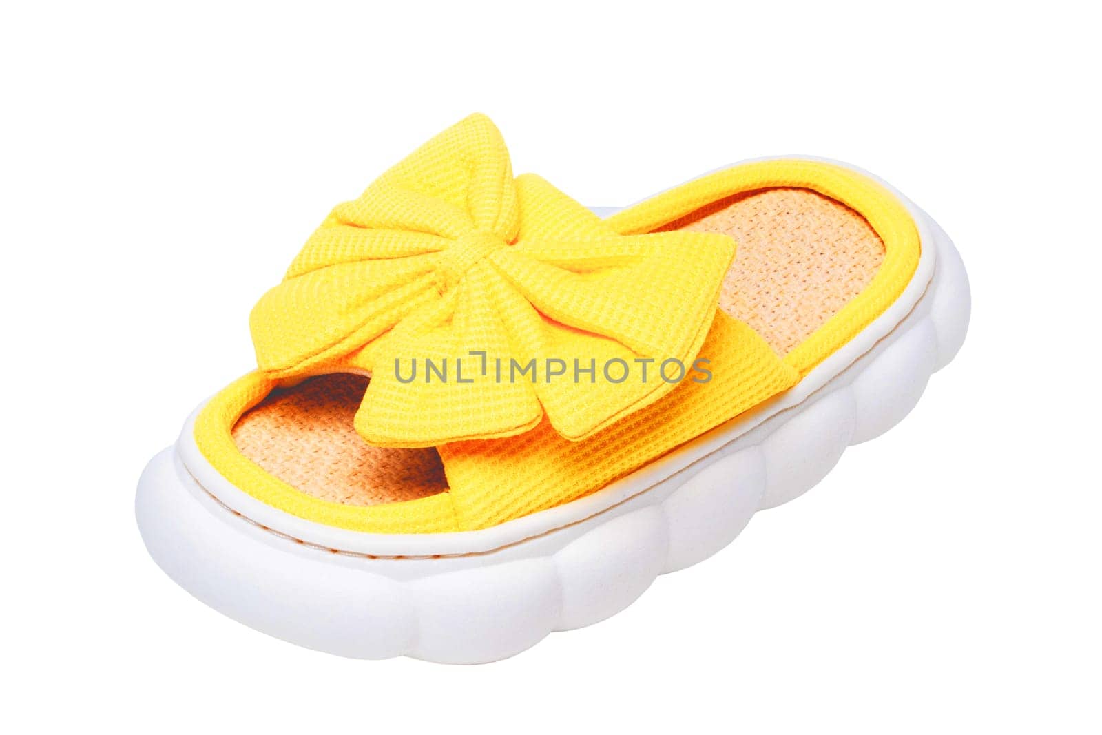 Slippers isolated. Close-up of a single female yellow soft cosy house slipper with a large bow isolated on a white background, Clipping path. Macro. Womans shoes.