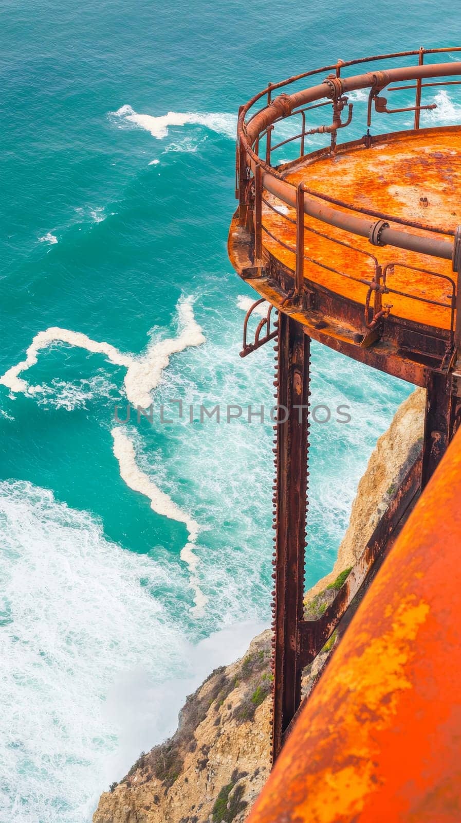 Weathered offshore platform with rusty orange railings overlooking crystal clear turquoise waters, showcasing contrast between industrial structures and natural beauty.
