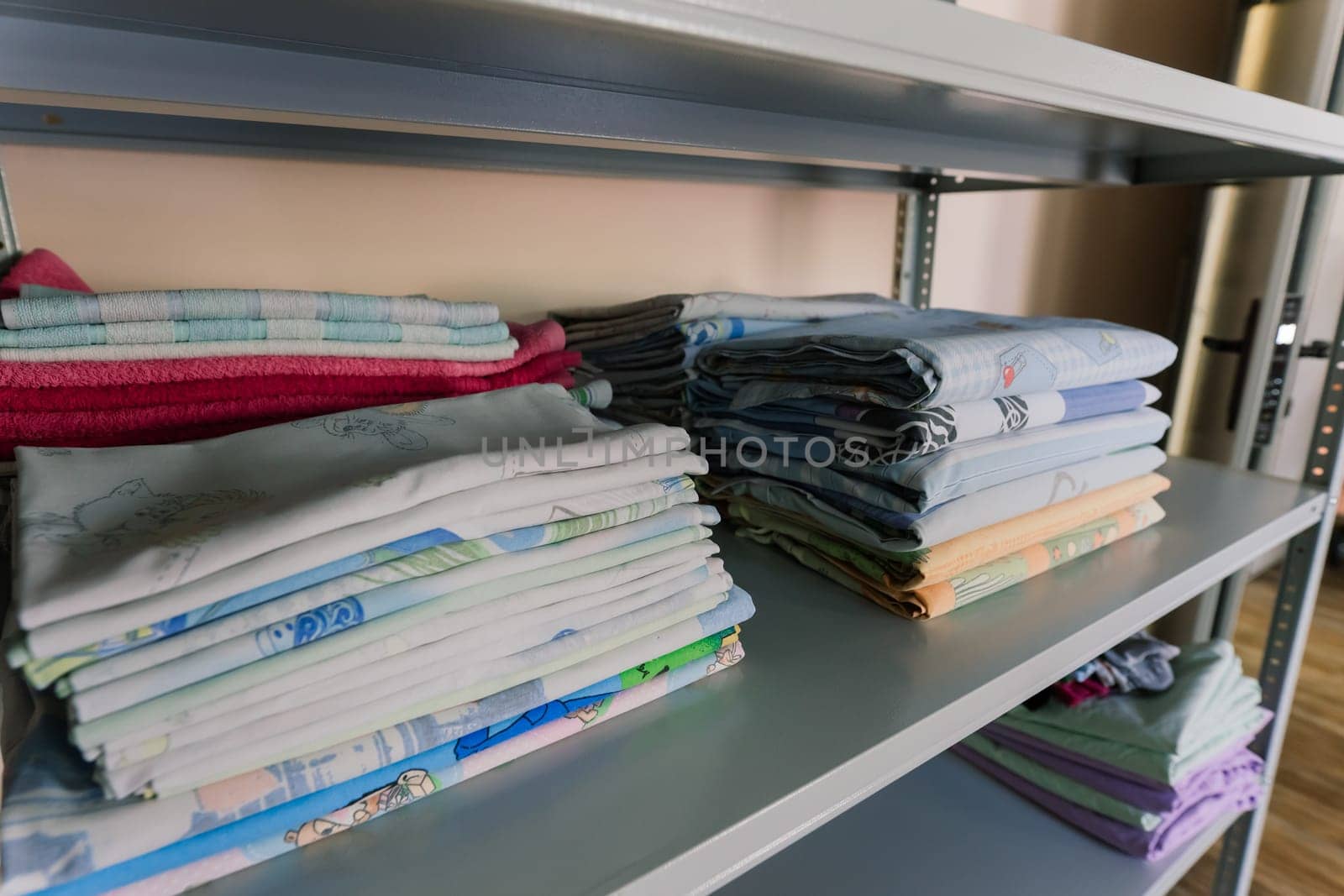 Linens piled neatly on the shelves. There are folded bed sheets, towels, wash clothes