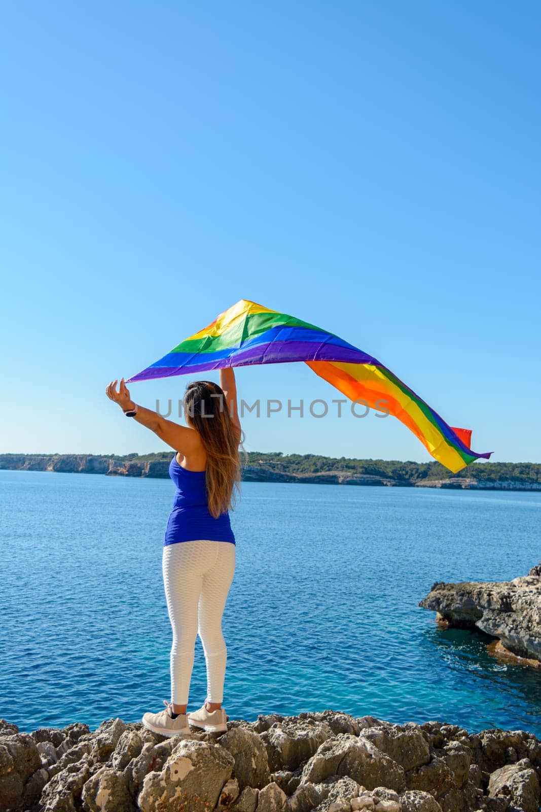 woman, middle aged, outdoors waving pride flag, concept of libertat, equality.