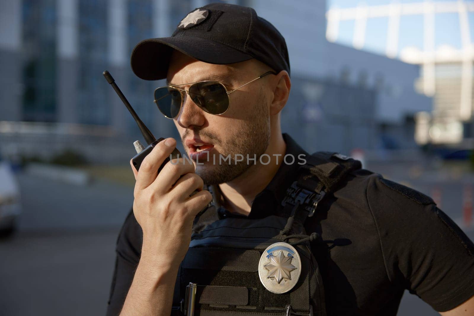Closeup portrait of male patrol police officer talking to radio while monitoring traffic stability and compliance with law on city streets